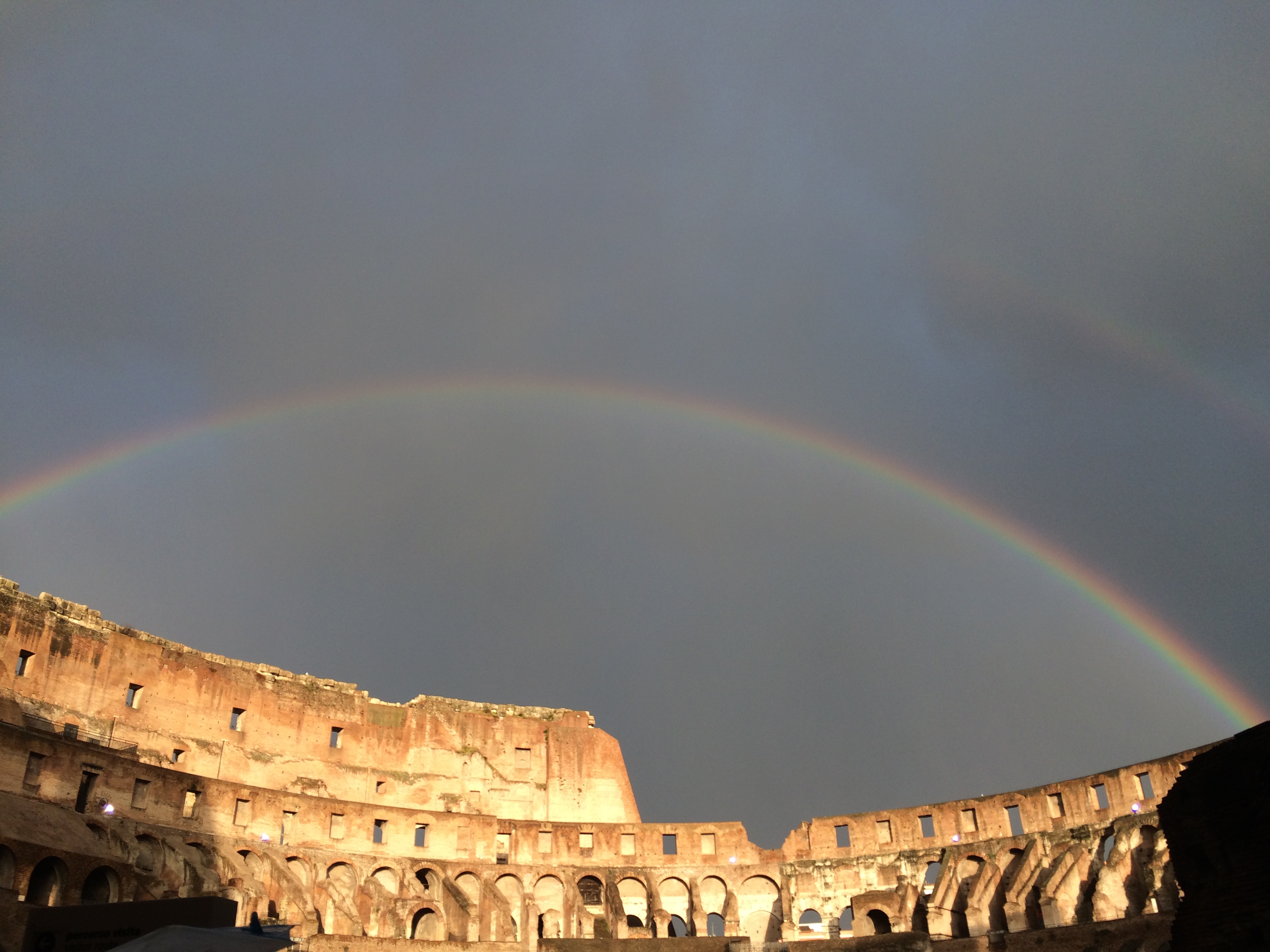 Double Rainbow above the Colosseum in Rome.  Sunshine and shadow in the foreground.  Cloud vapour streaking the sky.